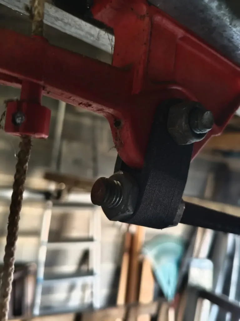 Biellette noire imprimée en 3D, boulonnée sur le châssis rouge d’une machine