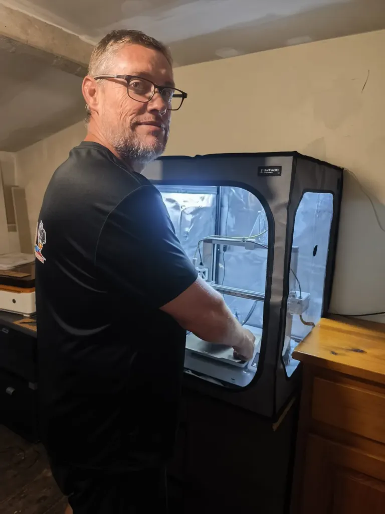 Le fondateur de Cam3D devant son imprimante 3D, à l’atelier
